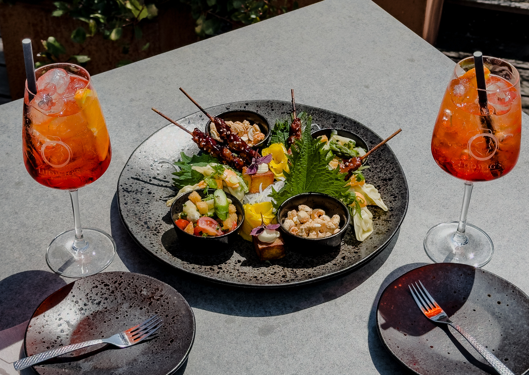 Snack-Teller und zwei Aperol Spritz auf einem Tisch mit zwei Tellern