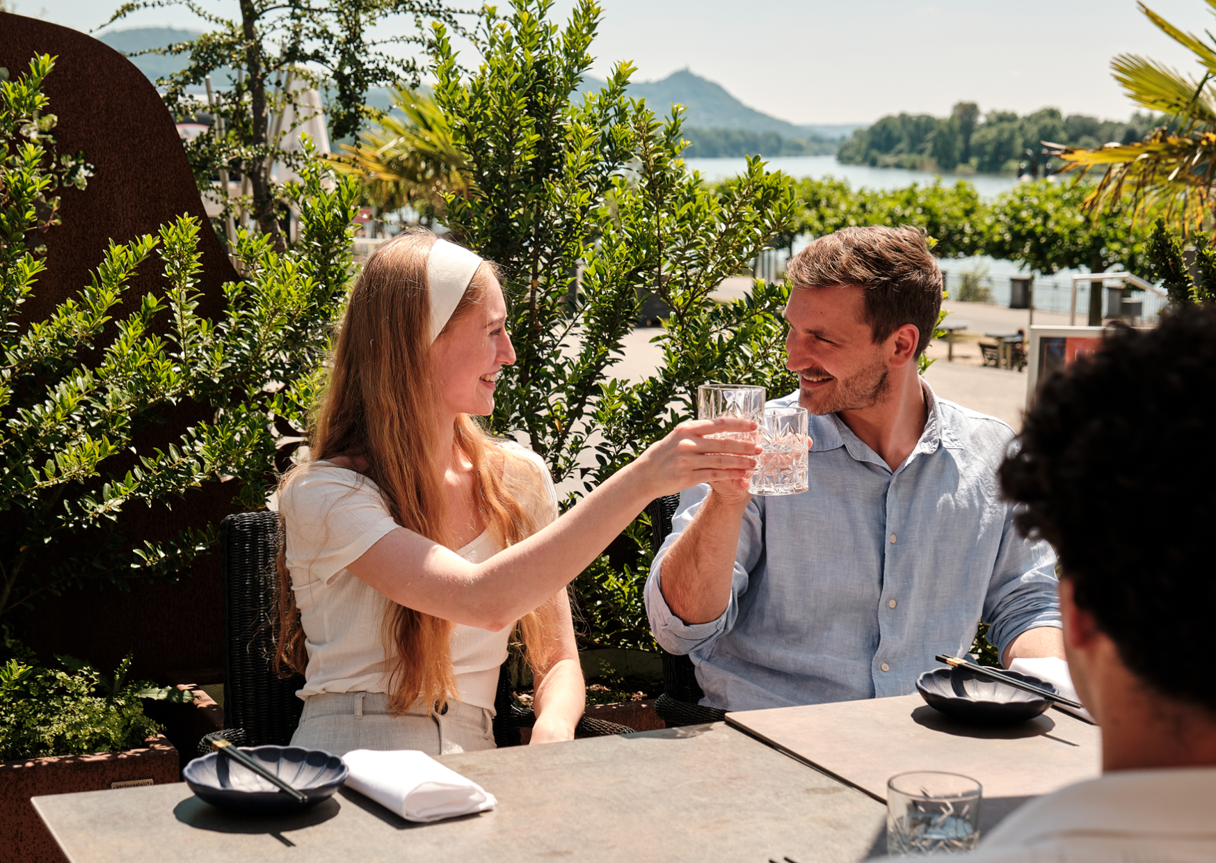 Glückliche Gäste genießen ihr Getränk auf der Terrasse mit Rheinblick